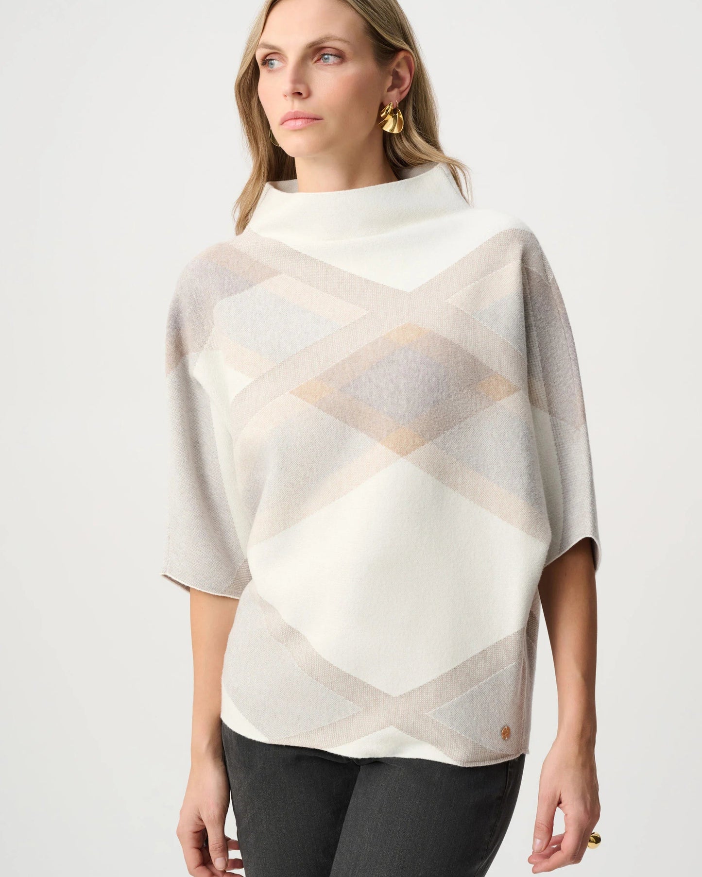 Woman wearing a patterned poncho against a white background