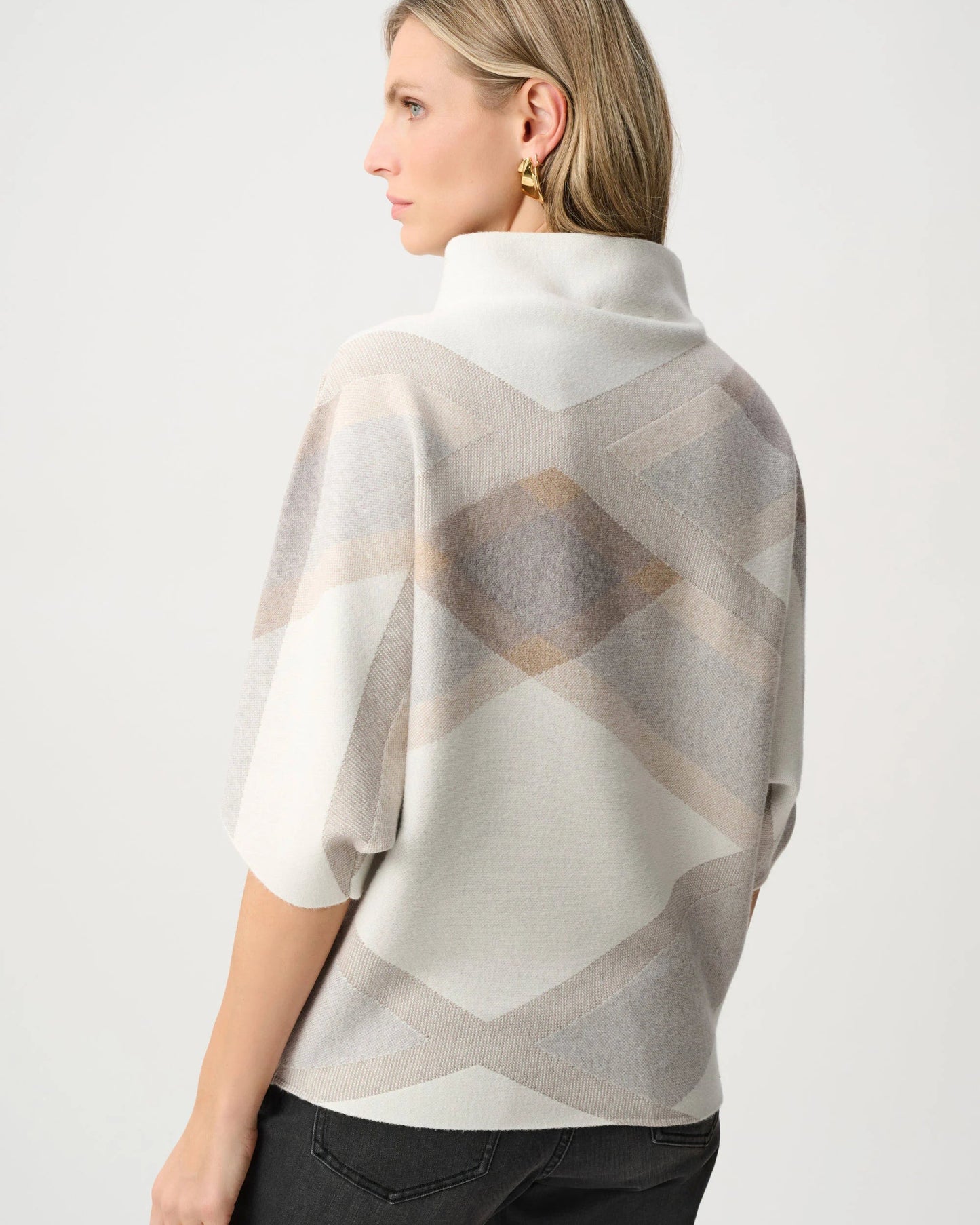 Woman wearing a patterned poncho against a white background