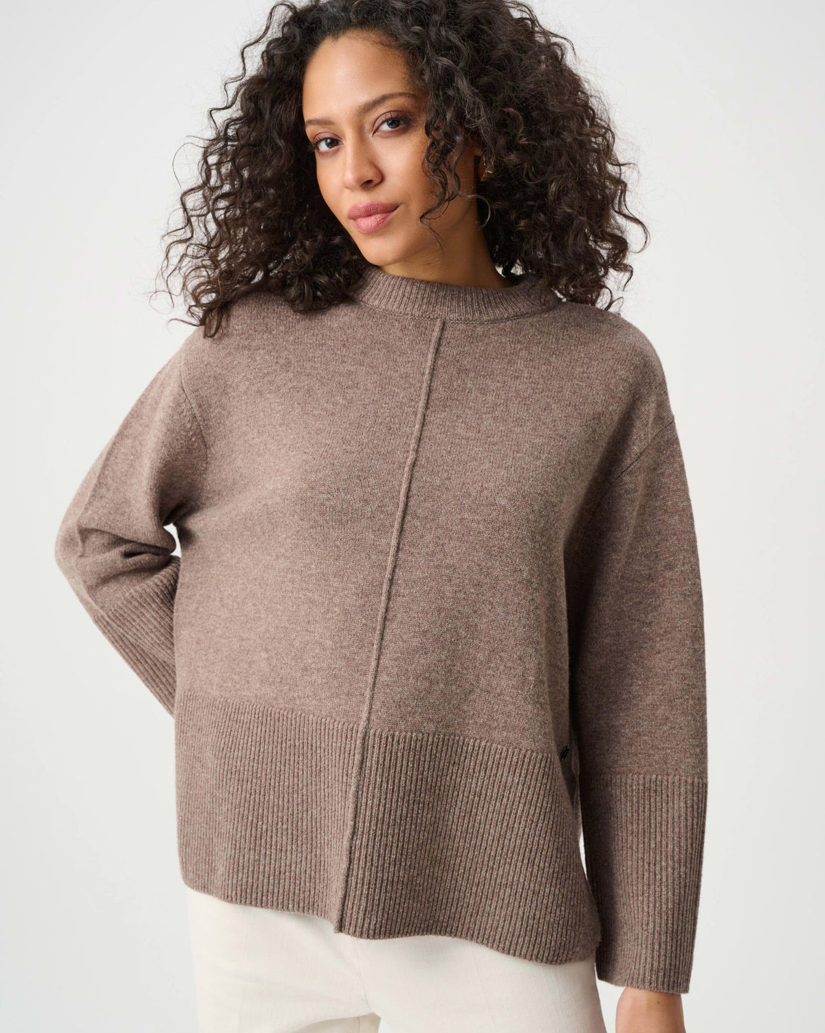 Woman wearing a brown sweater against a white background
