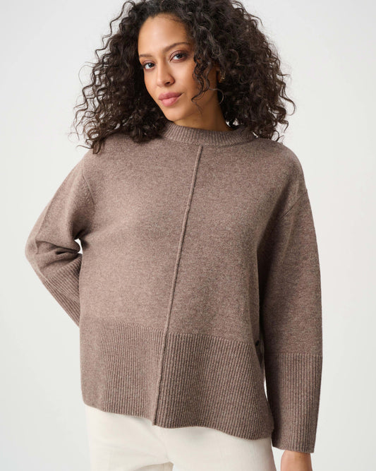 Woman wearing a brown sweater against a white background