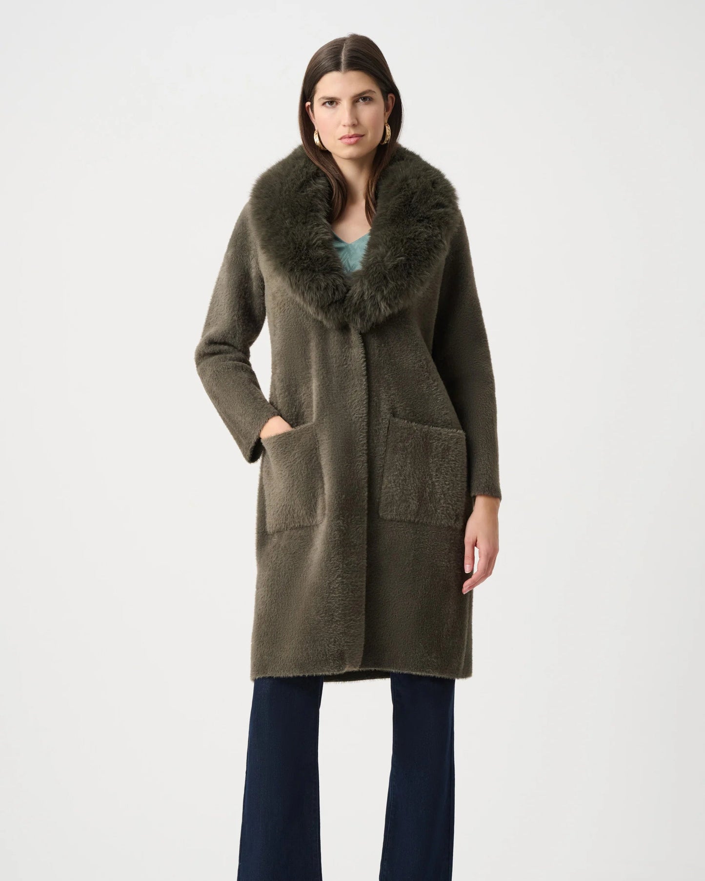 Woman wearing a long olive green coat with fur collar on a white background