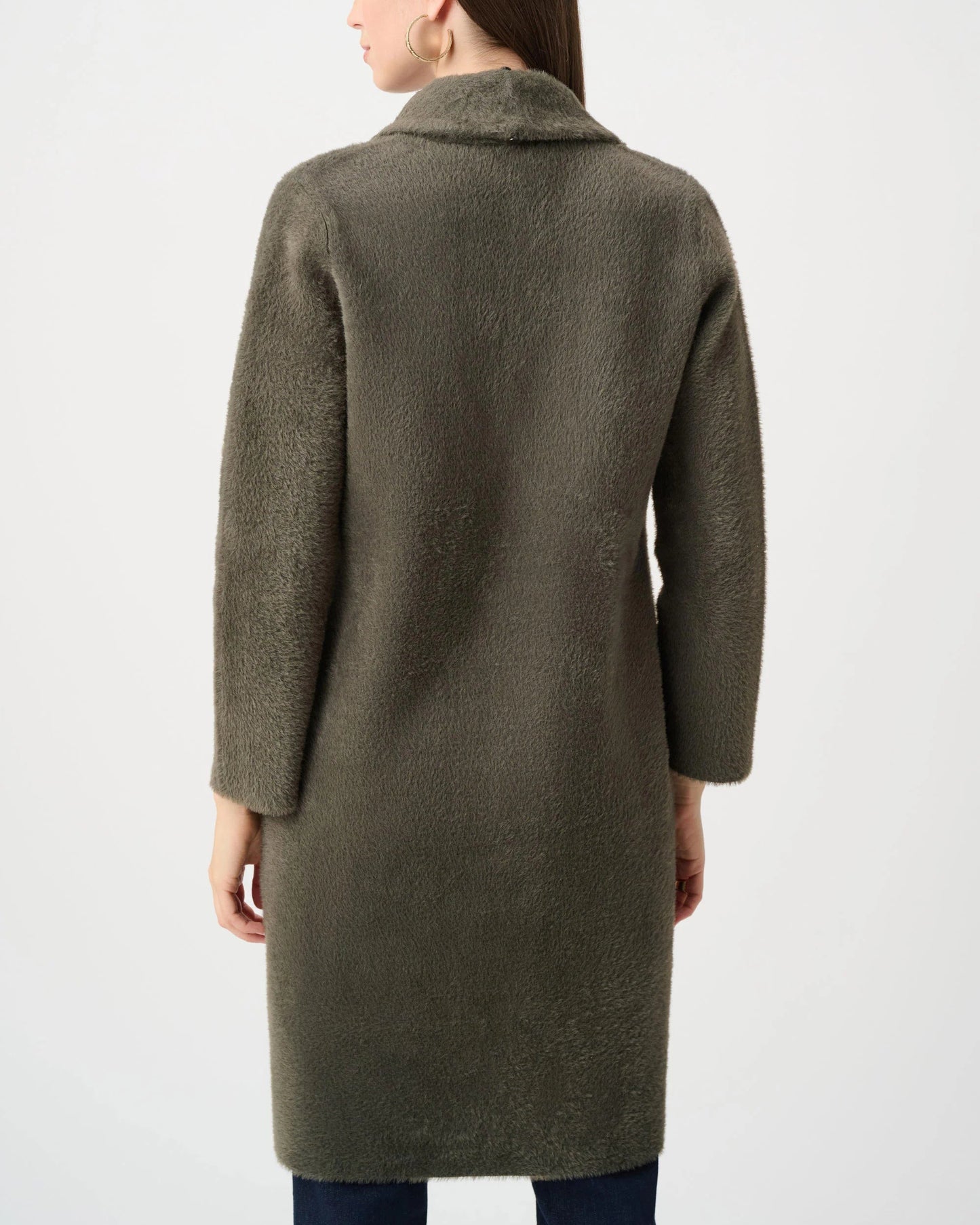 Woman wearing a long olive green coat on a white background