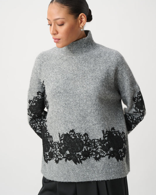 Woman wearing a gray sweater with black floral patterns on a white background