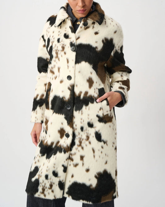 Woman wearing a cow print jacket in front of a white background.