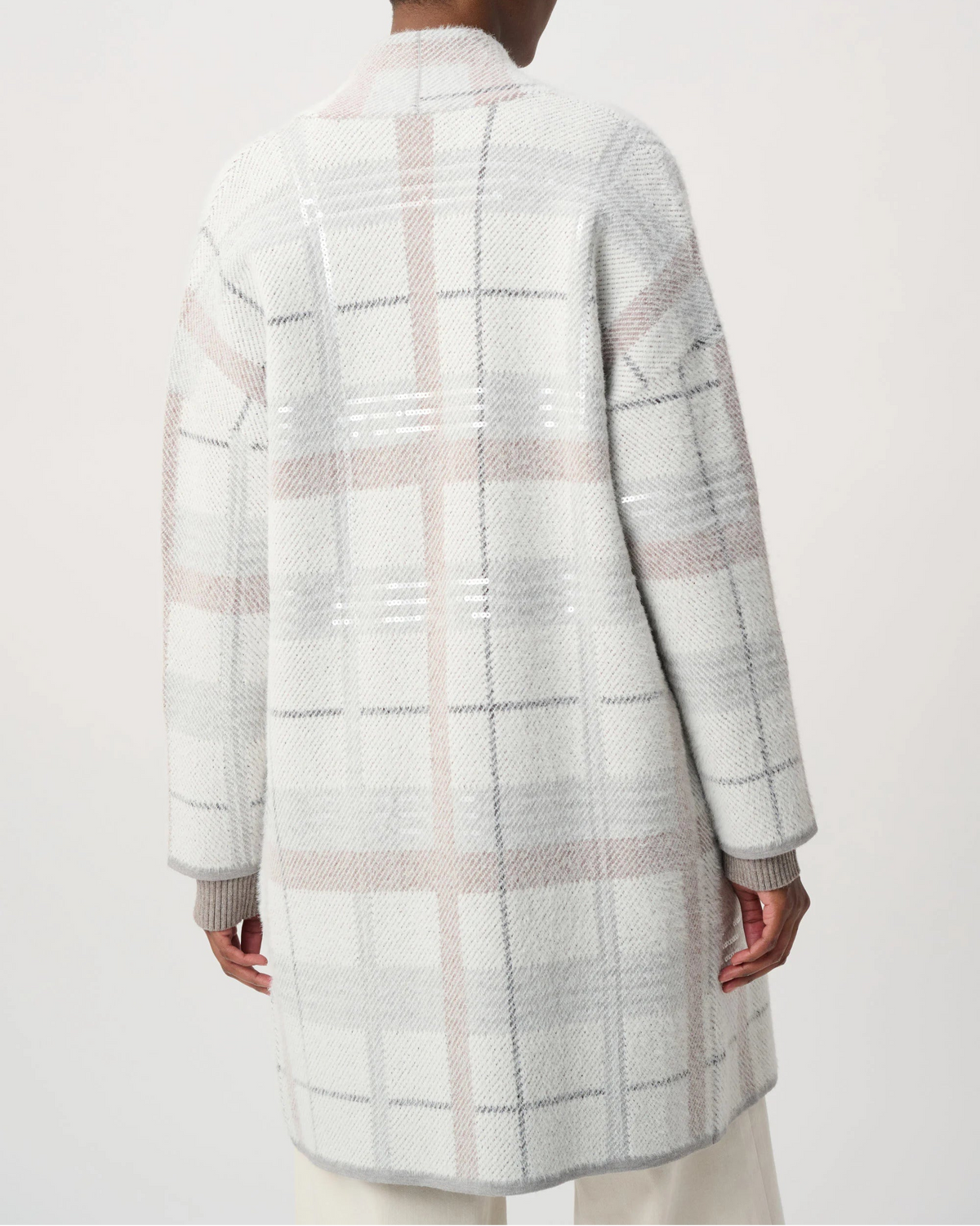 A model shown from the back wearing a long-sleeve, mid-length plaid coat in white, light gray, and soft pink. The coat features a textured knit pattern with intersecting vertical and horizontal plaid lines.