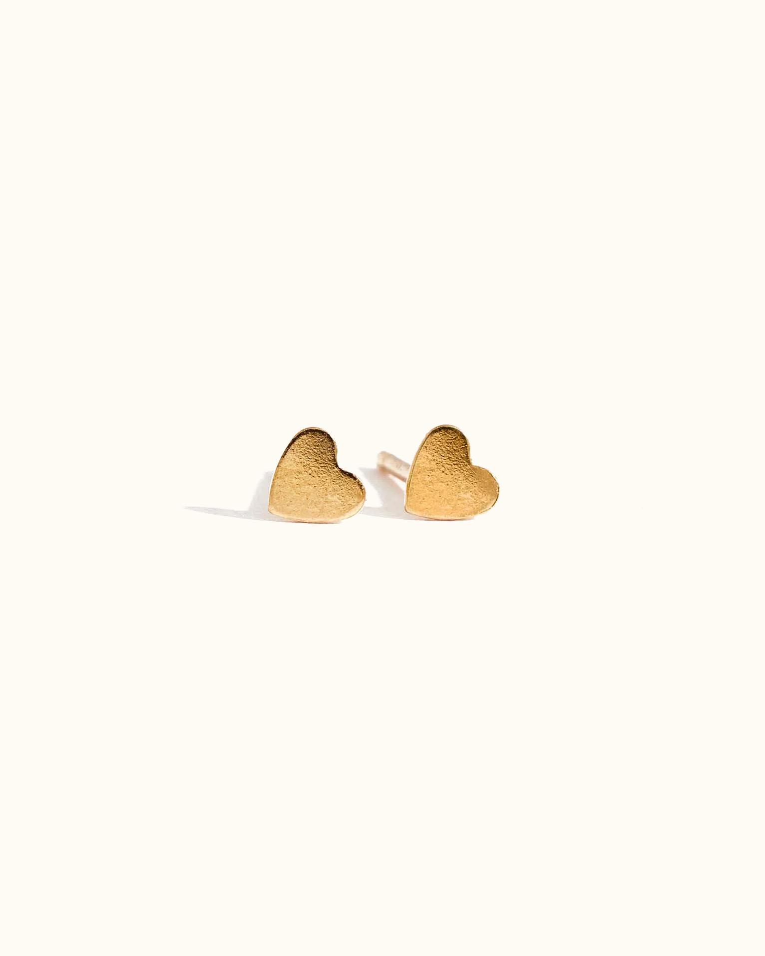 Gold heart-shaped earrings on a white background