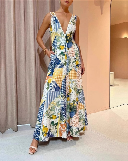 Model is wearing Rosa Clothing Le Vigen Lemon & Floral Maxi Dress with tan sandals on a sand colored background