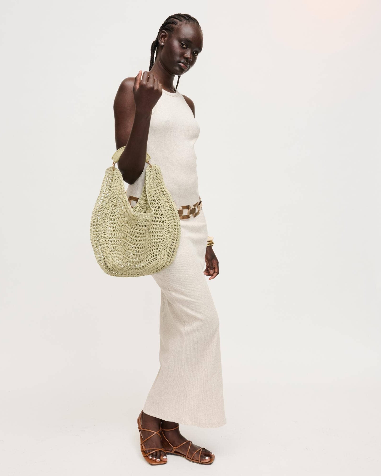 Woman holding a green woven bag against a white background