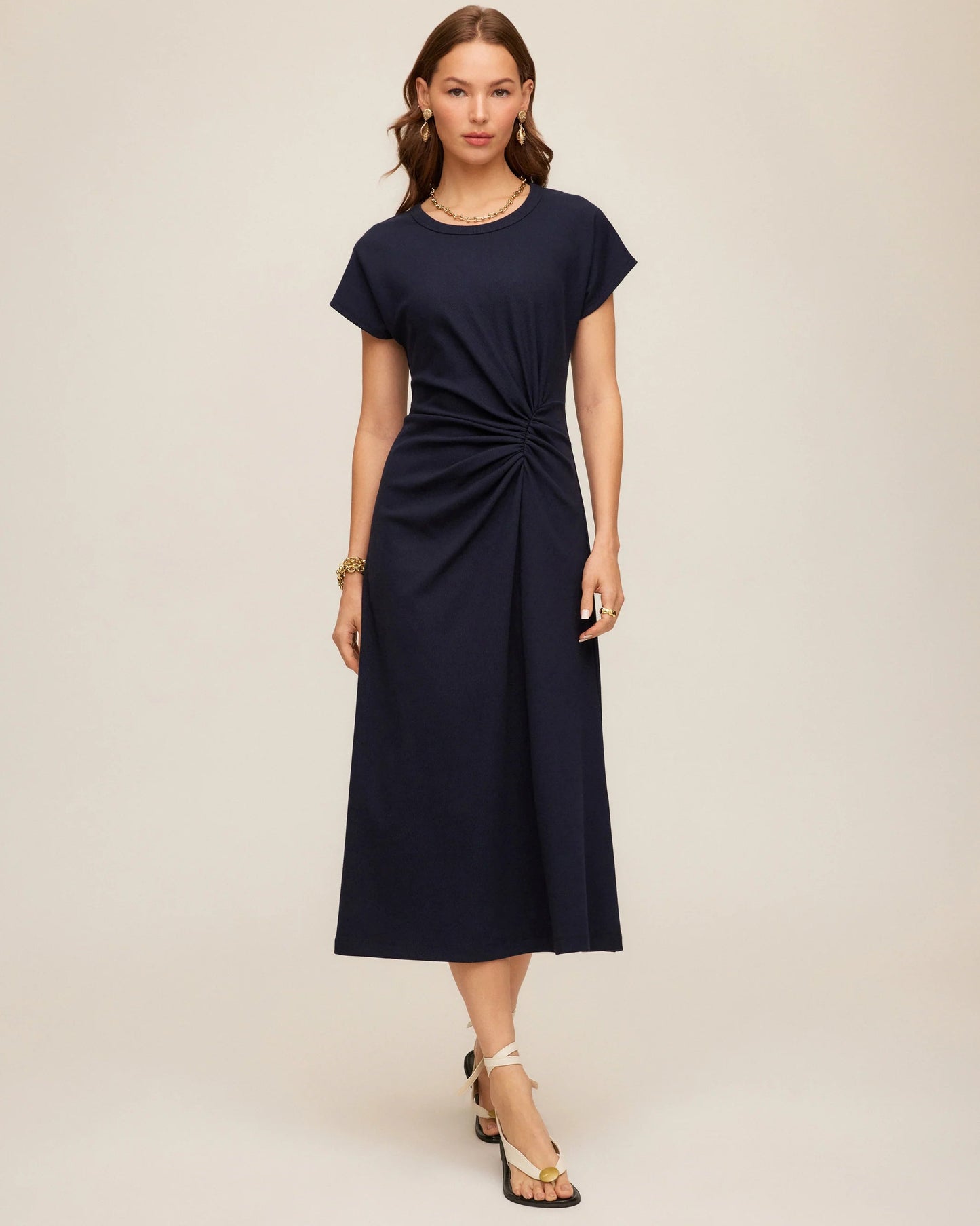 Woman wearing a navy blue dress with a knot detail on a beige background