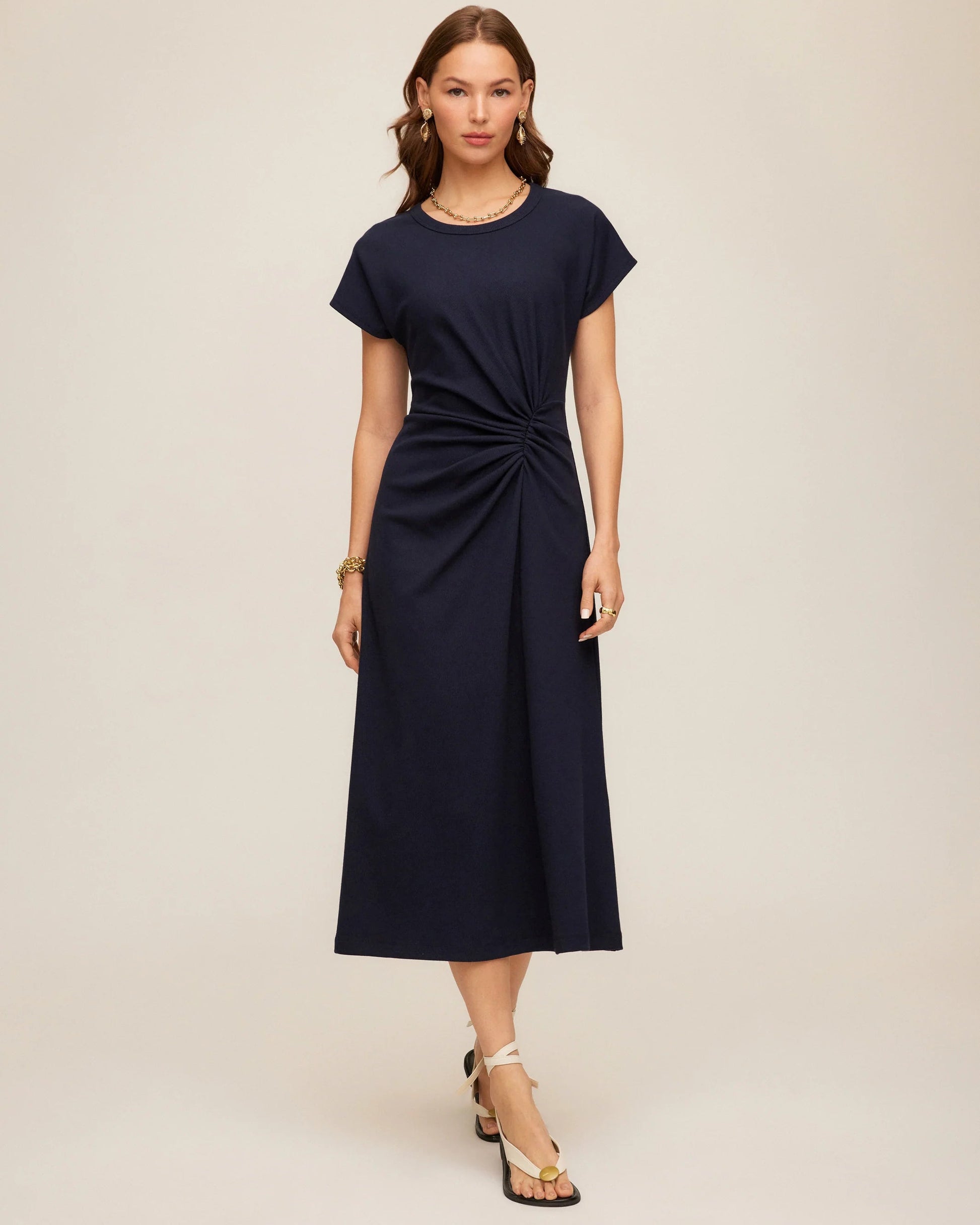 Woman wearing a navy blue dress with a knot detail on a beige background