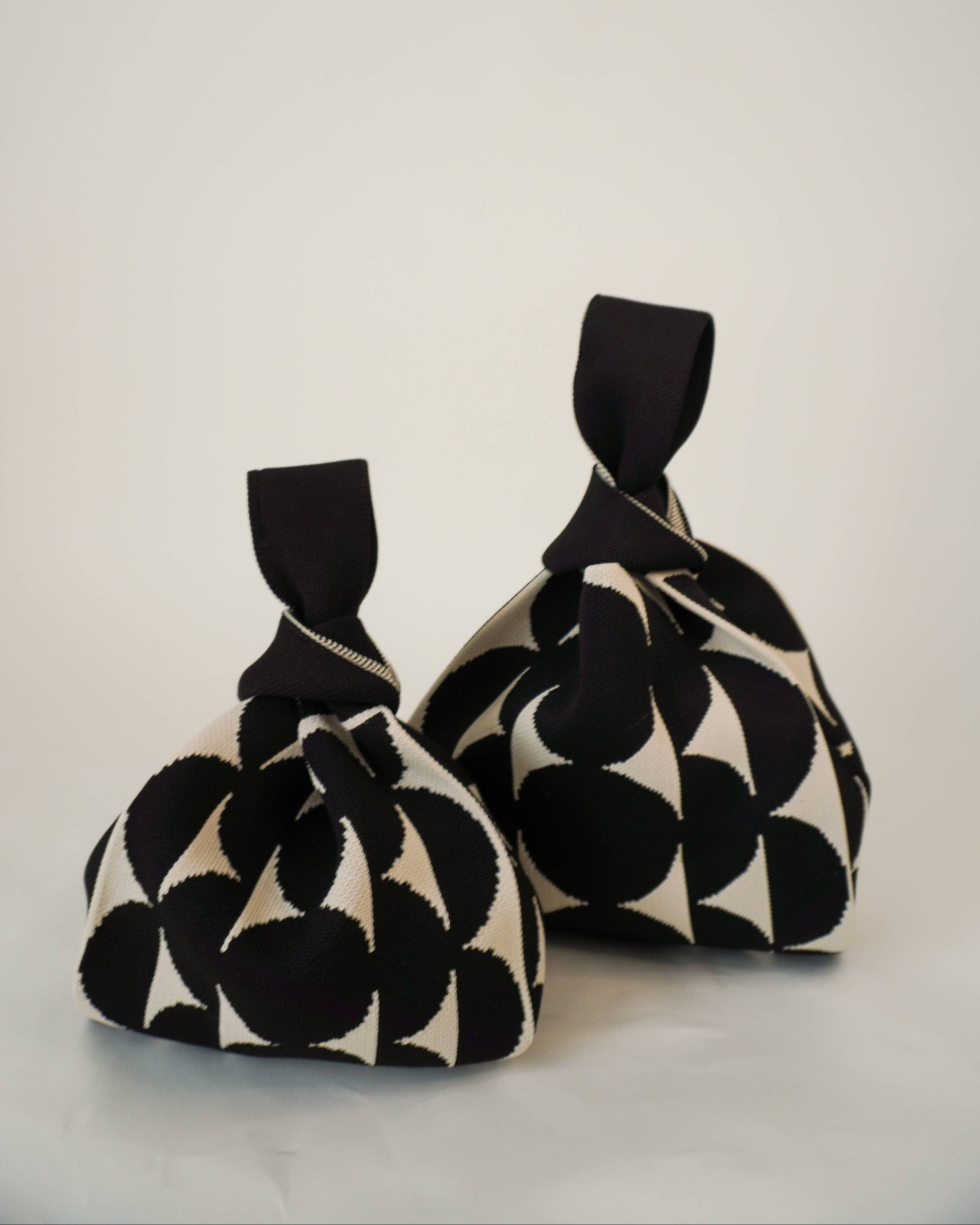 Two black and white patterned fabric bags on a light gray background