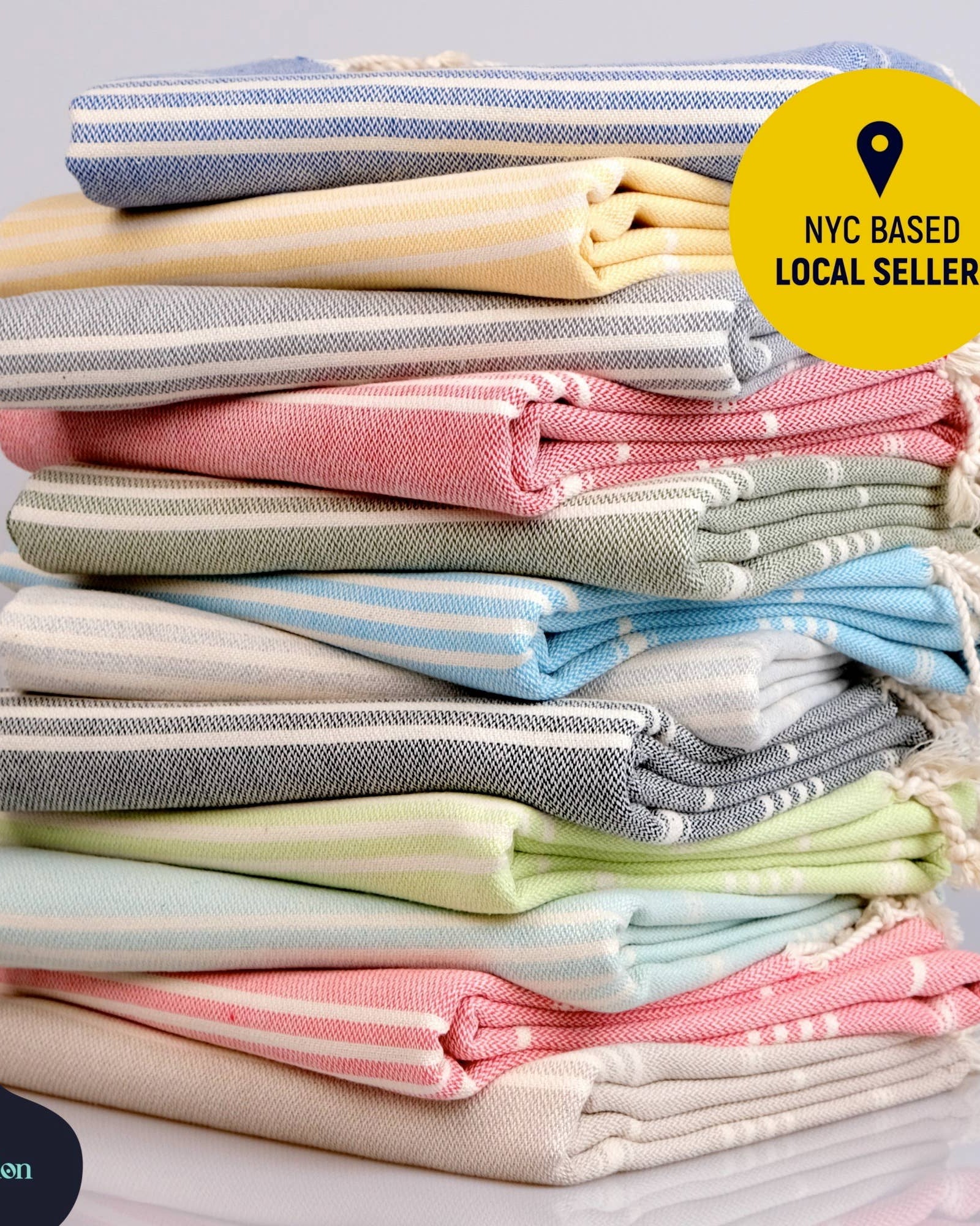 Stack of folded towels in various colors with a 'NYC Based Local Seller' badge and Kalbadun logo.