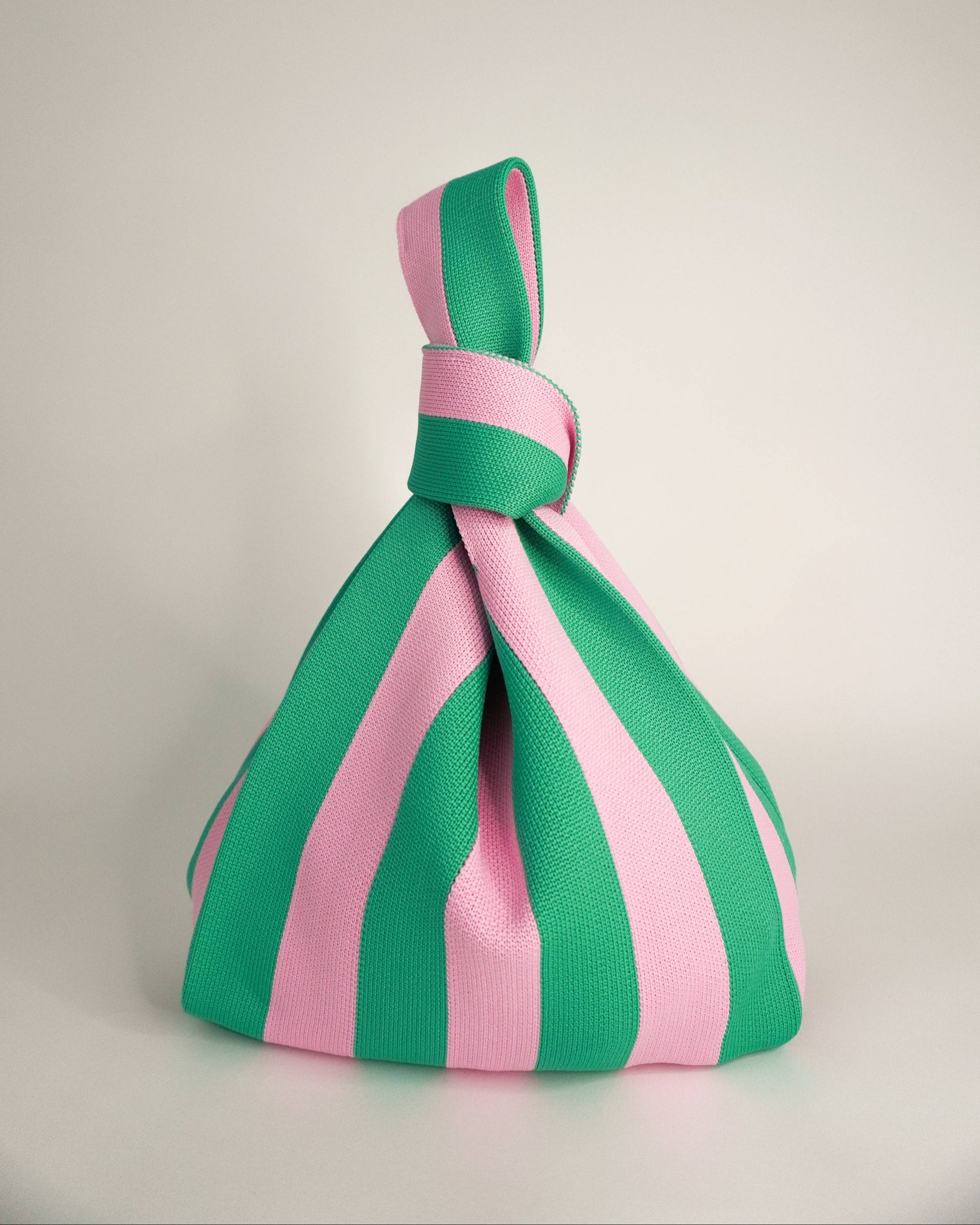 Green and pink striped knot on a light gray background