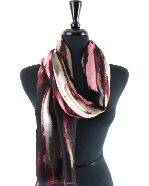 A lightweight scarf with an abstract brushstroke pattern in burgundy, pink, beige, and black, draped on a black mannequin torso against a white background.
