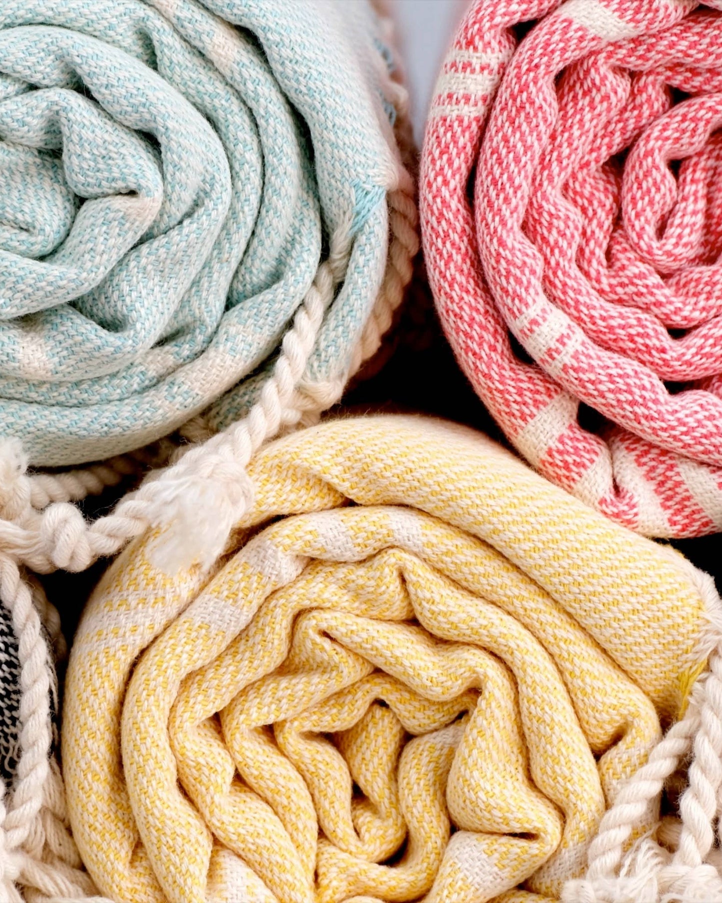 Three rolled-up fabrics in pastel colors with a brand logo in the corner.
