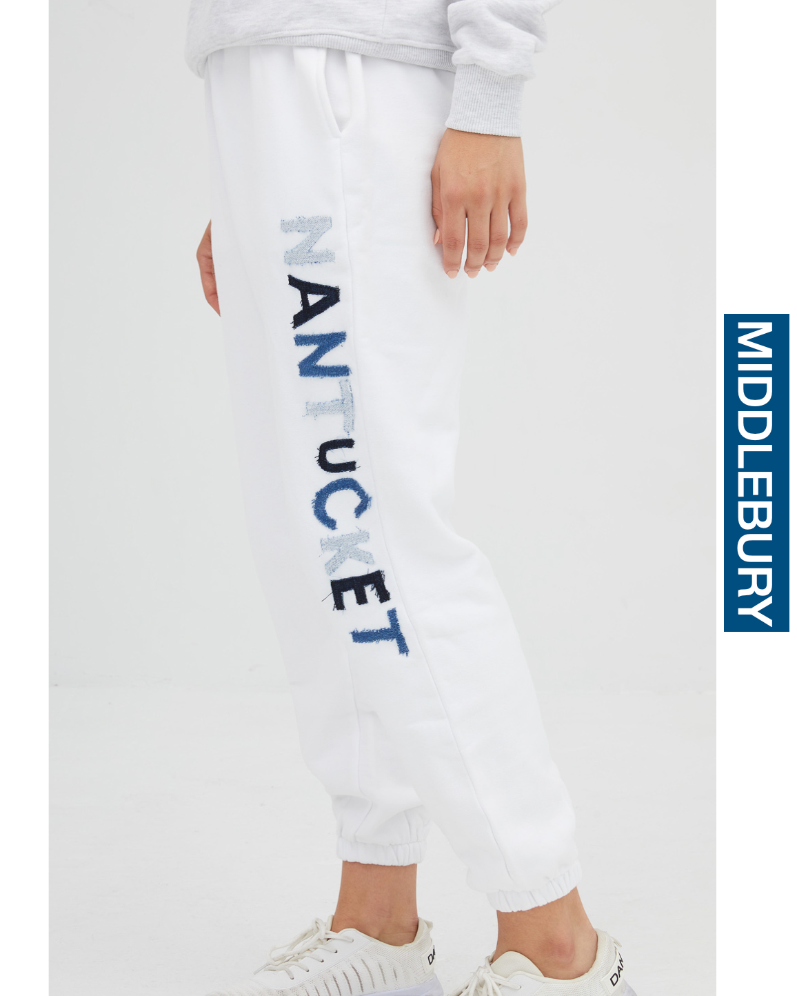 Model wearing Unemployed Denim Letter Sweatpants saying MIDDLEBURY in white on a white background