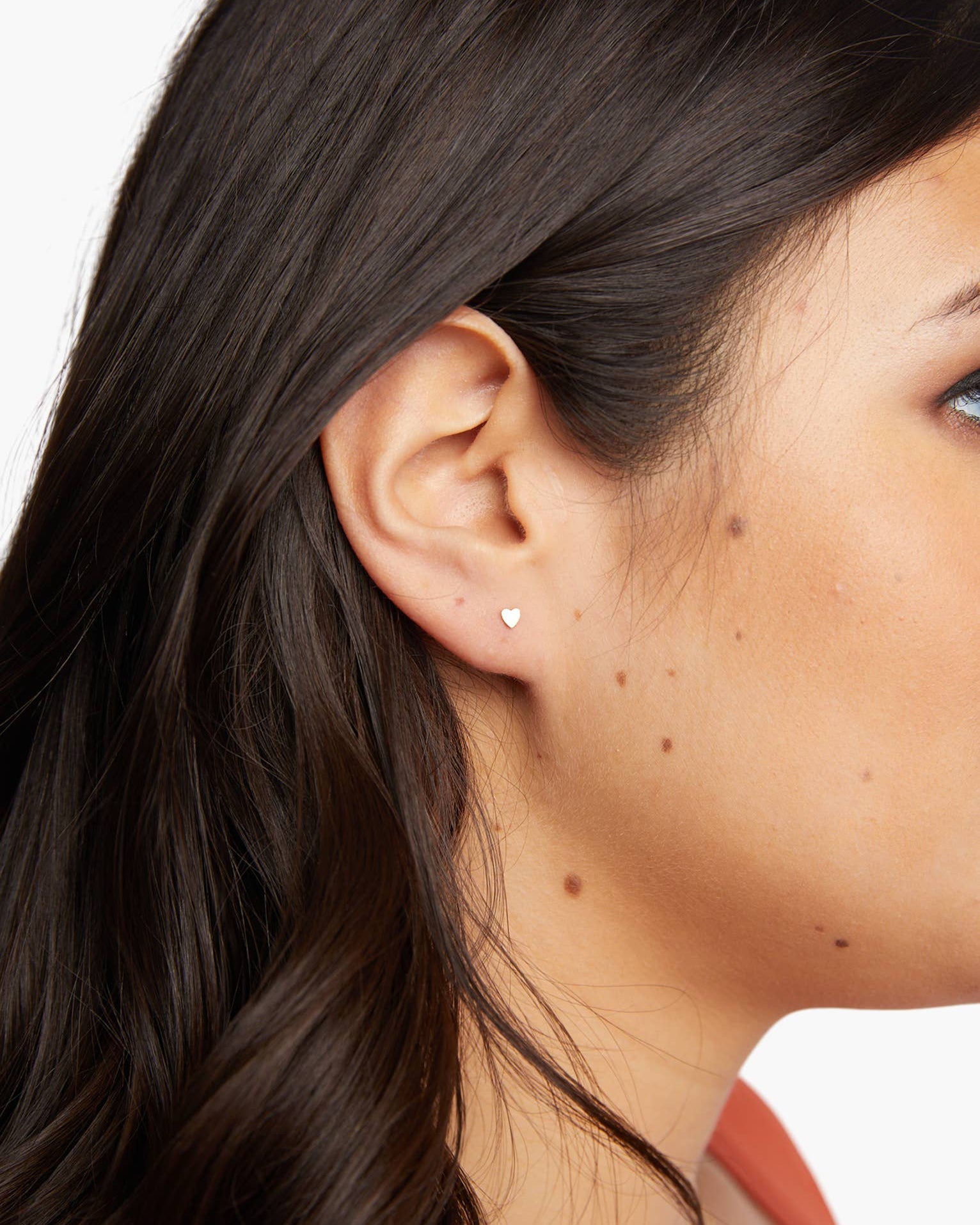 Close-up of a person wearing a heart-shaped earring on a white background