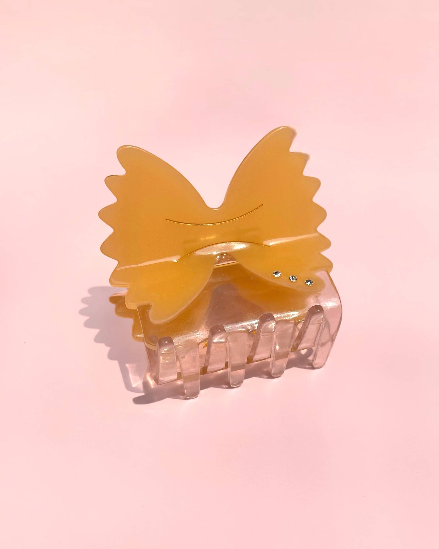 Butterfly-shaped hair clip with a clear base on a pink background