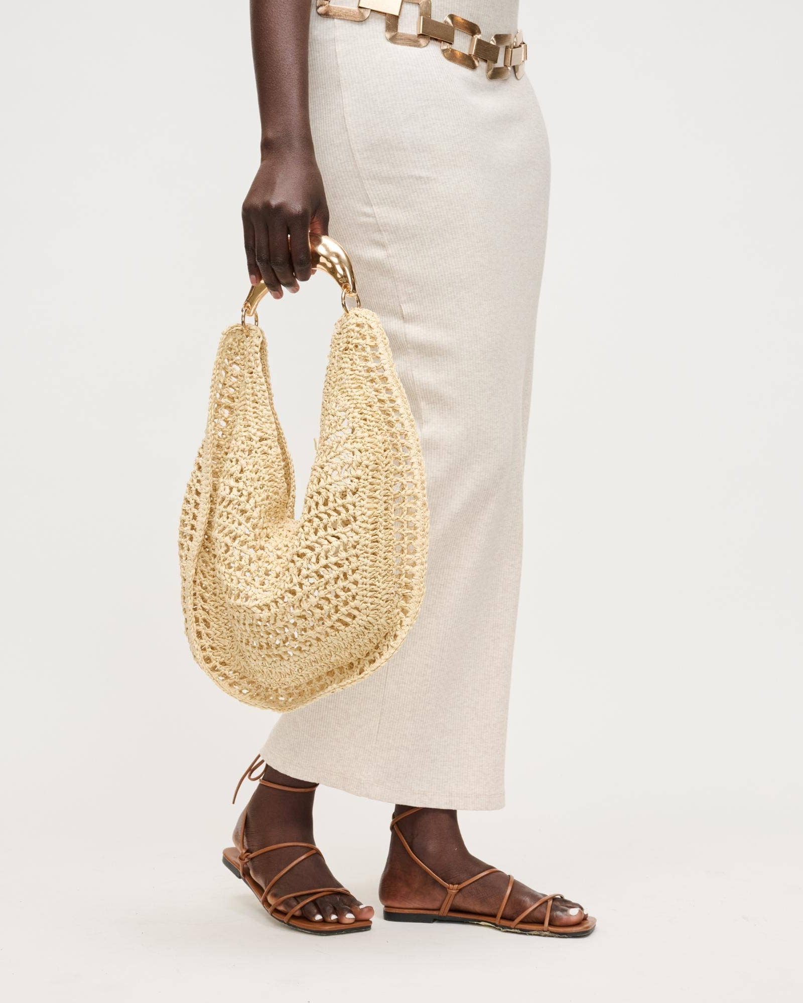 Person holding a woven handbag with a plain background