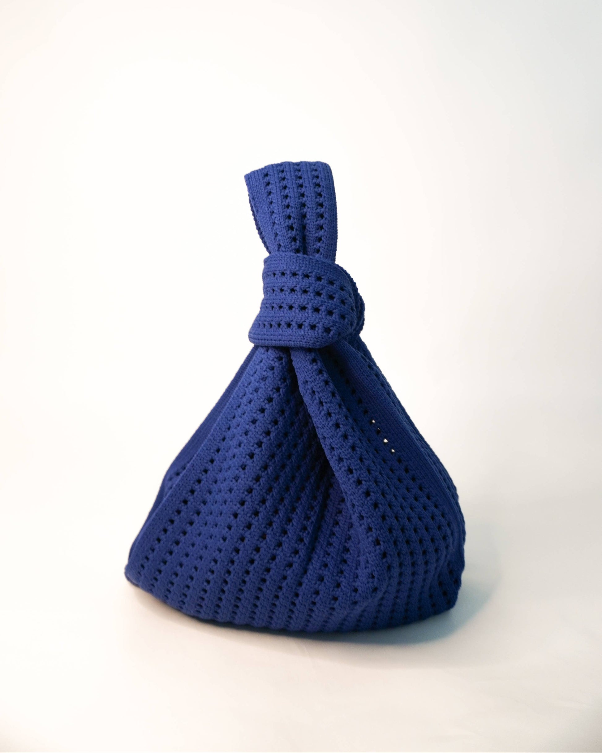 Blue knotted fabric bag on a white background