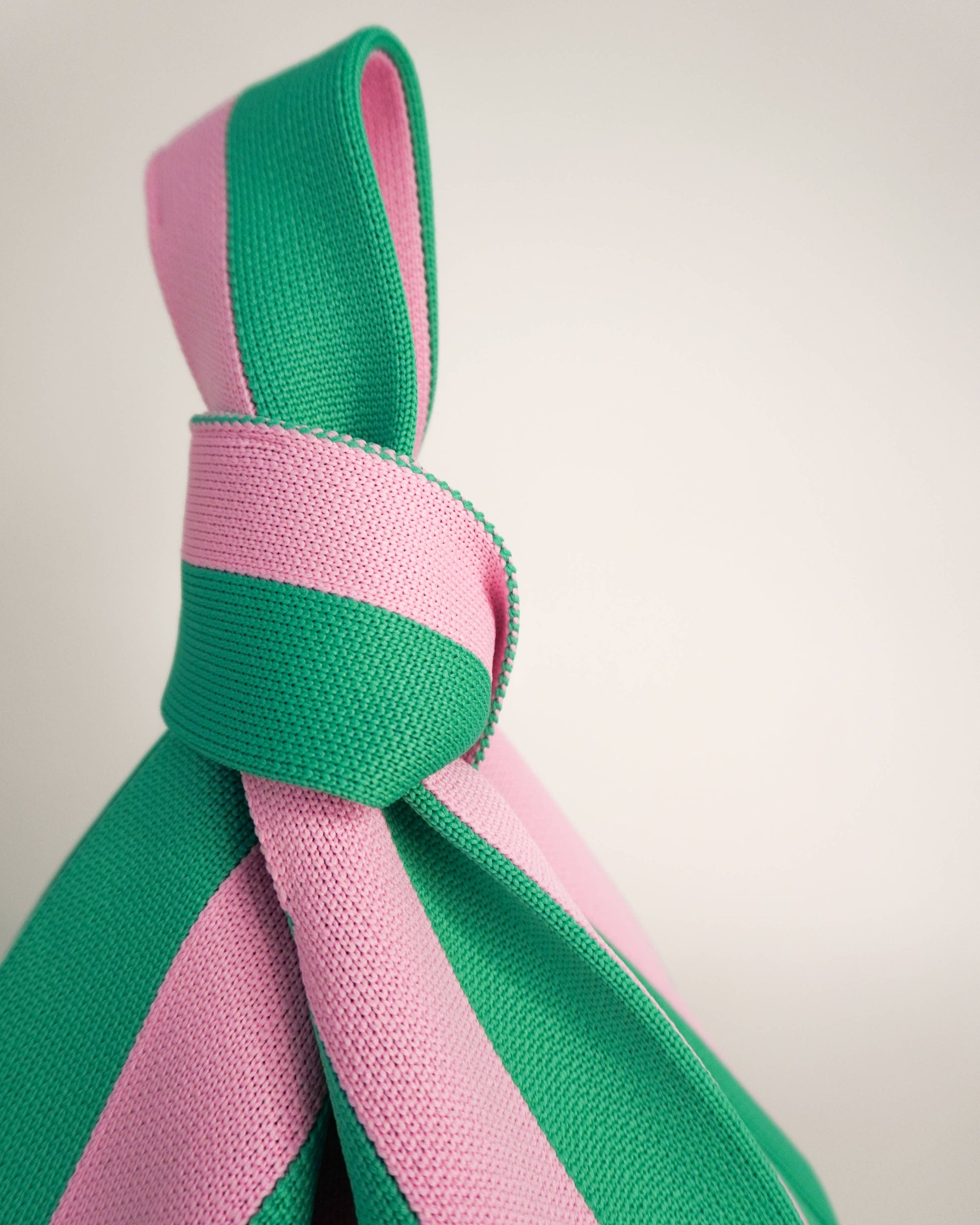Close-up of a pink and green bag tied in a knot on a light background
