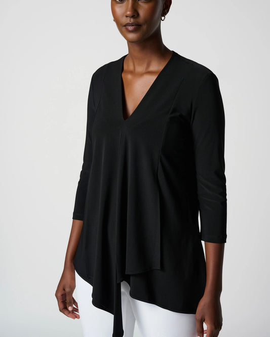 Front view of a model wearing the Joseph Ribkoff long sleeve asymmetrical top in black standing in front of a white background.