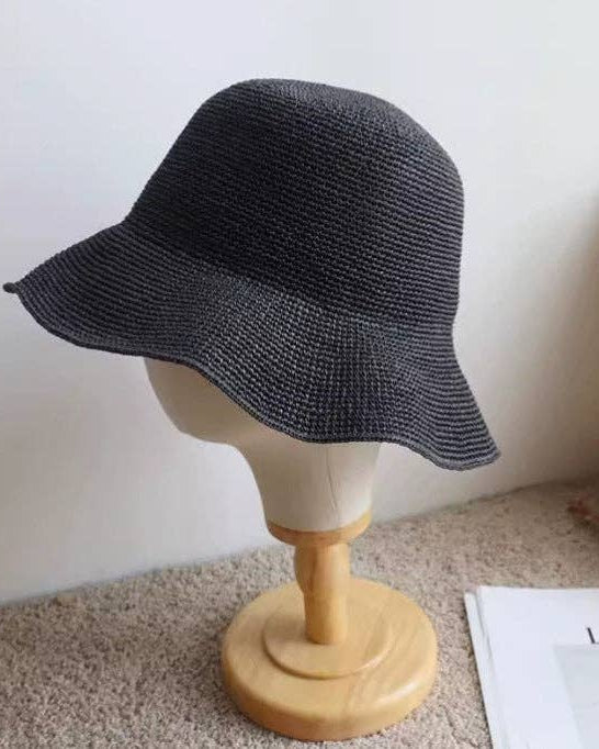 Black straw hat on a mannequin head against a white wall.