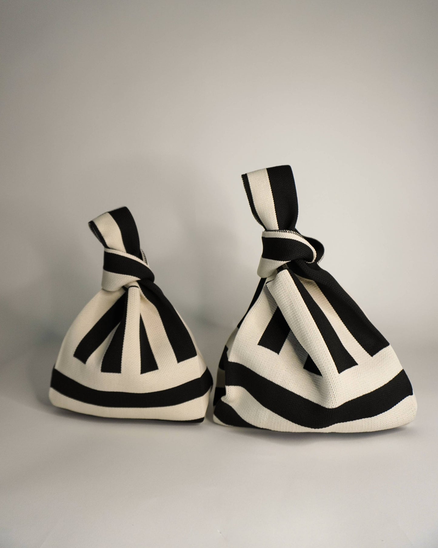 Two black and white striped bags on a gray background