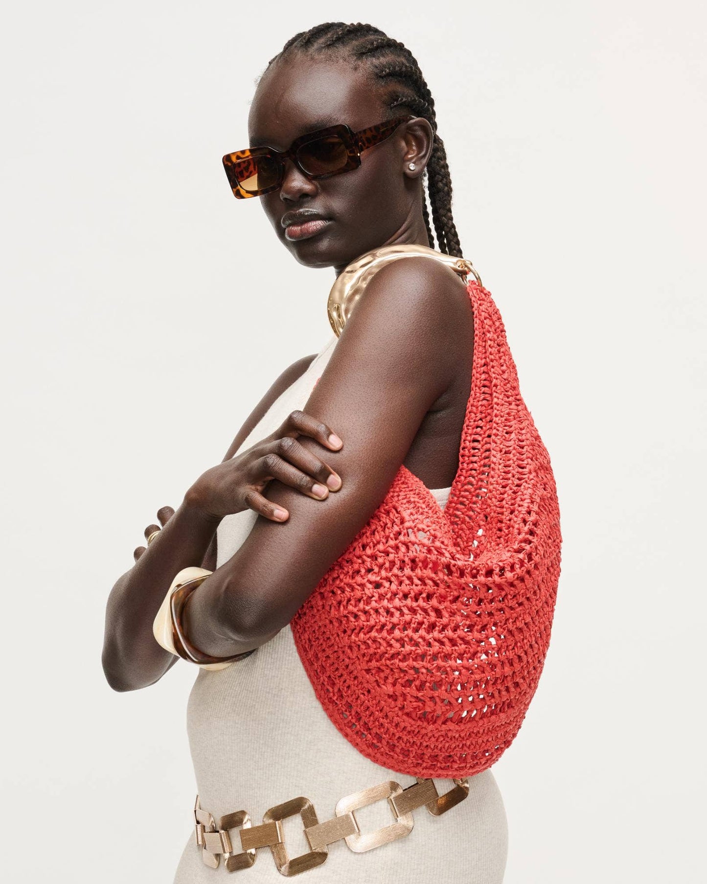 Woman wearing a red woven bag on a plain background