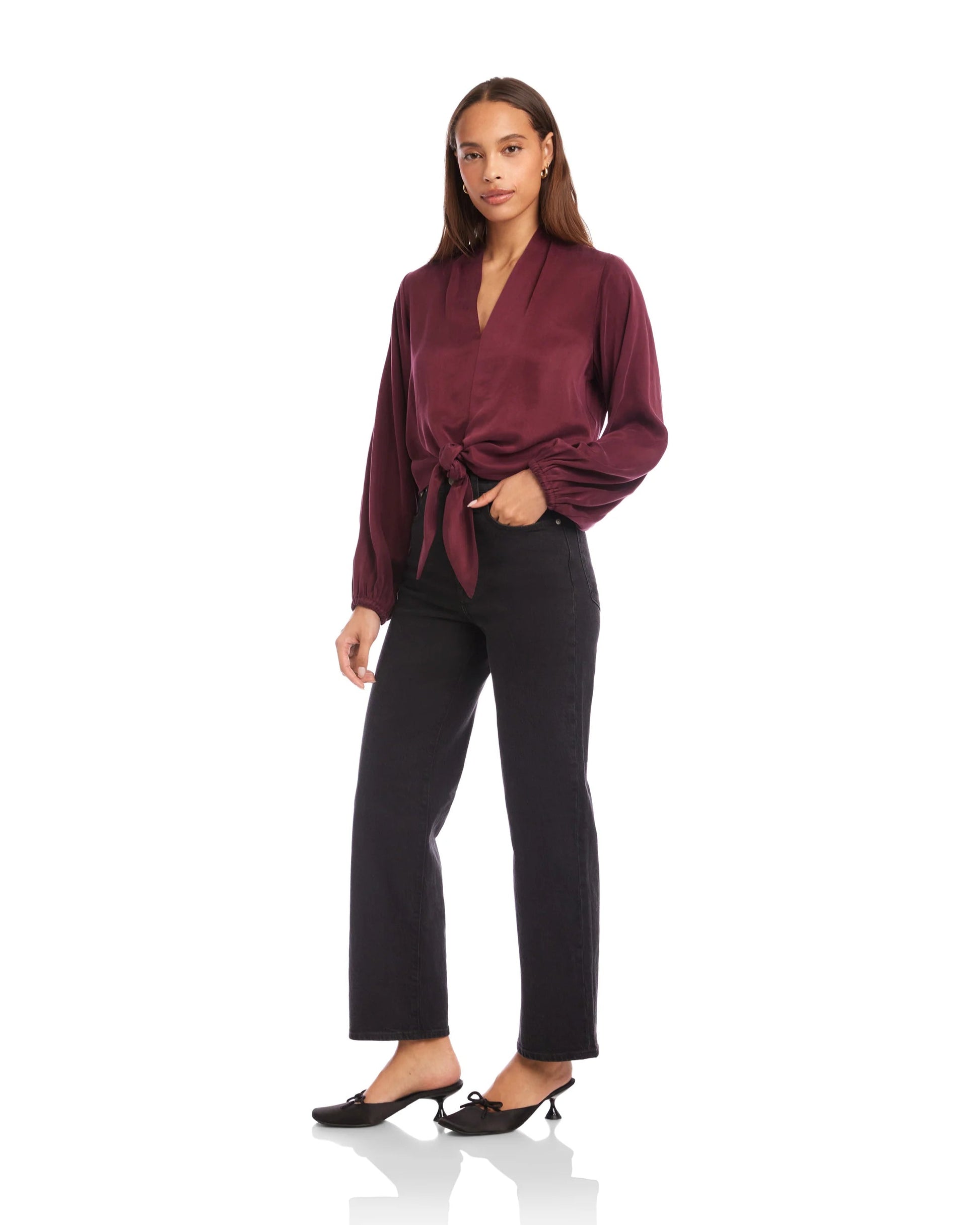 Woman wearing a burgundy wrap top and black pants on a white background