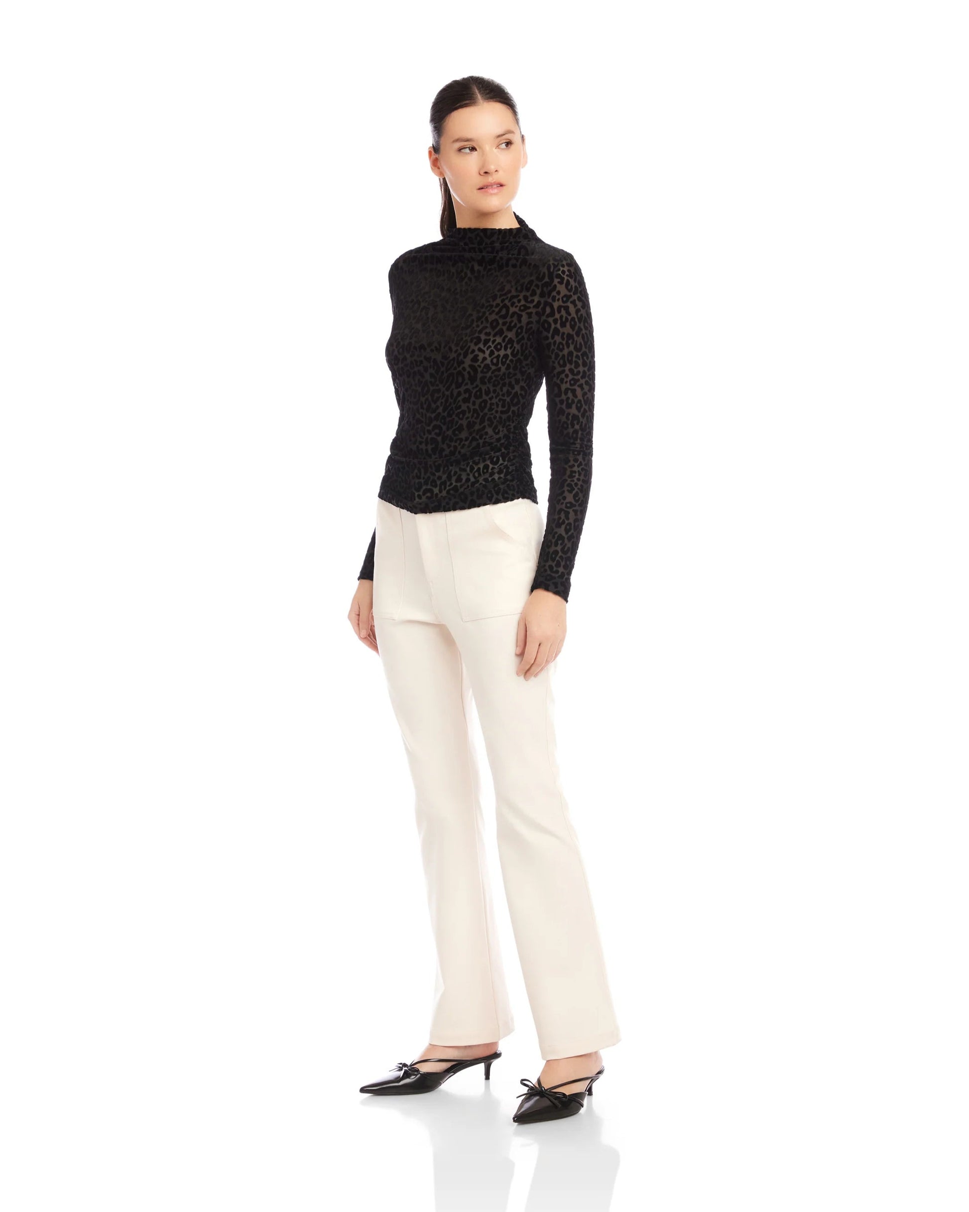 Woman wearing a black turtleneck and white pants on a white background