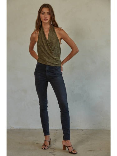 Model wearing By together Eva metallic halter top wearing jeans and black heels on a gray background