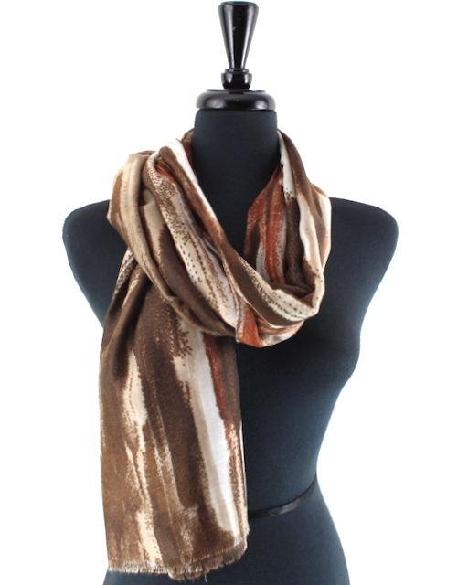 A long scarf with an abstract brushstroke pattern in brown, beige, and rust orange, draped on a black mannequin torso against a white background.