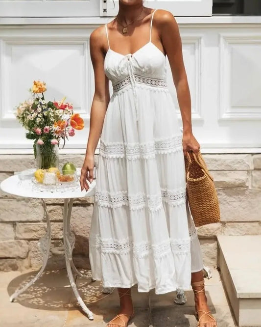 Model is wearing Rosa Clothing Boho Lace Slip Dress in white with a woven bag and tan sandals on a white and floral background
