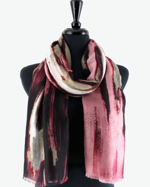 A lightweight scarf with an abstract painterly pattern in pink, burgundy, black, and beige, draped on a black mannequin torso against a plain white background.