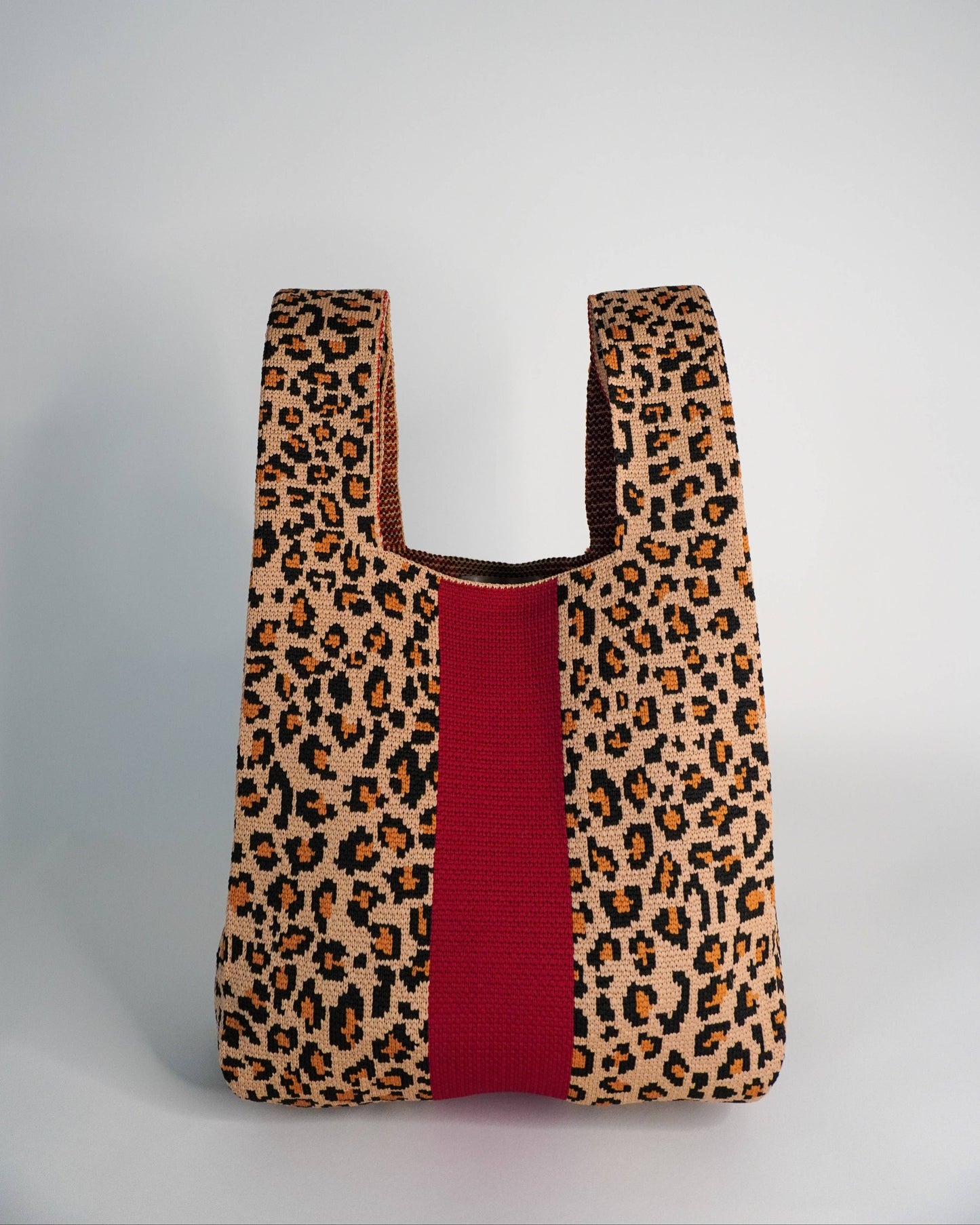 Leopard print bag with a red stripe on a gray background