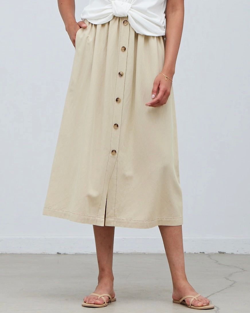 Model wearing Grade & Gather Button Down Midi Skirt in washed natural color wearing white tee on a white background