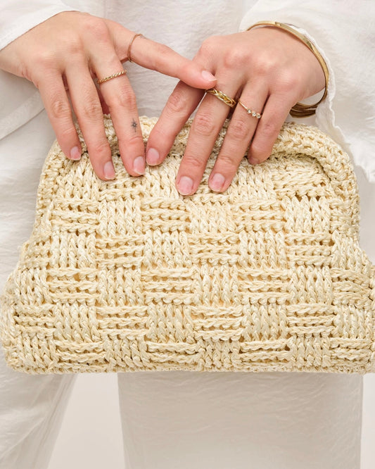 Detail photo of the Urban Expressions Annie clutch being held by a model wearing a neutral color outfit