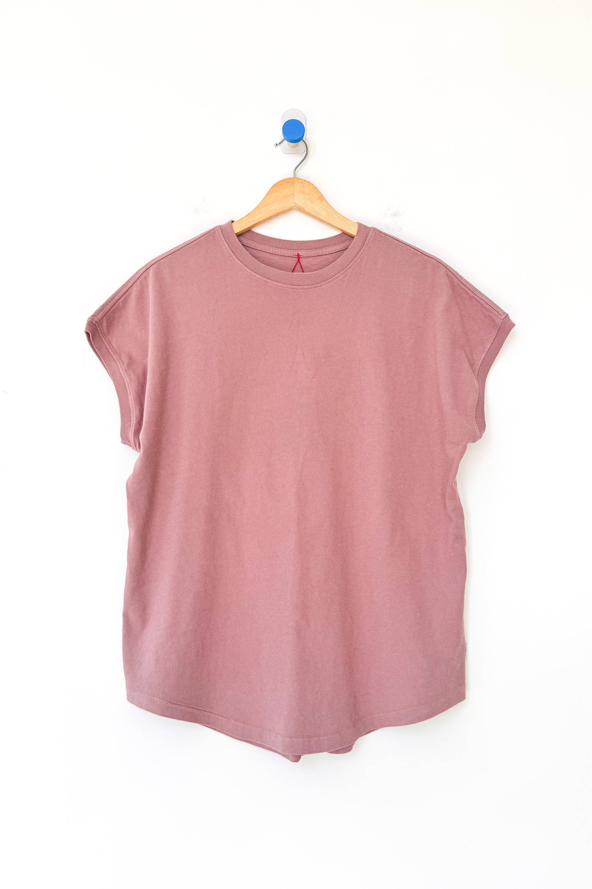 Mauve sleeveless top on a wooden hanger against a white background