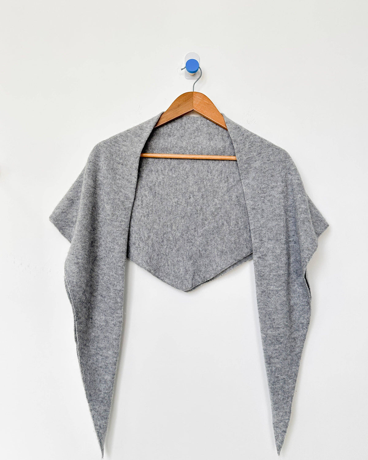 Gray shawl on a wooden hanger against a white background