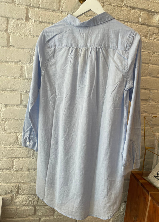 Image of Dylan Maya sky blue tunic hanging on a white brick wall