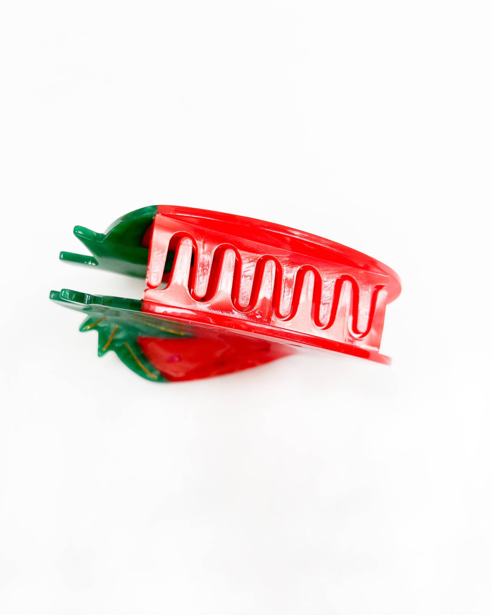 Red and green plastic hair clip on a white background