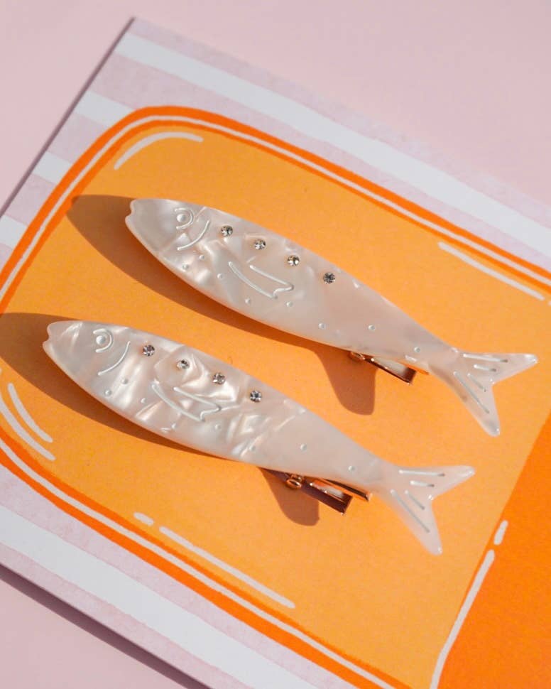 Two fish-shaped hair clips on a pink and orange background