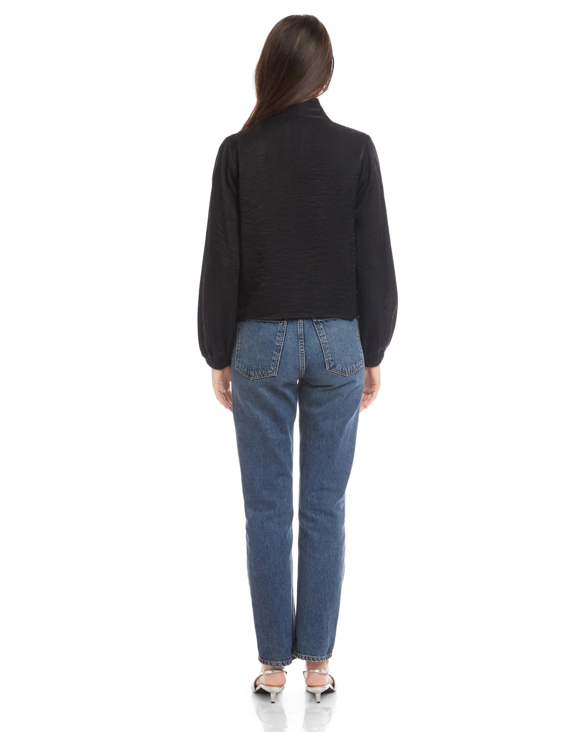 Person wearing a black jacket and blue jeans on a white background