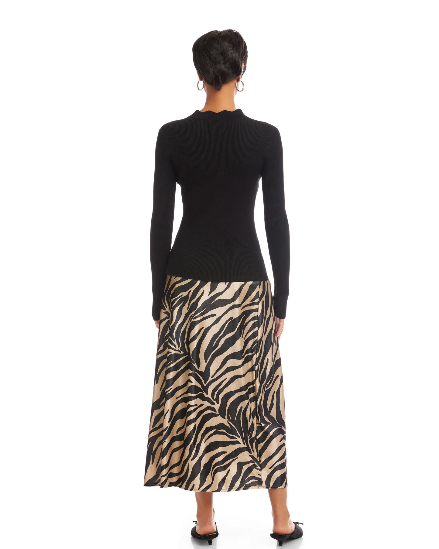 Person wearing a black long-sleeve top and zebra print skirt on a white background