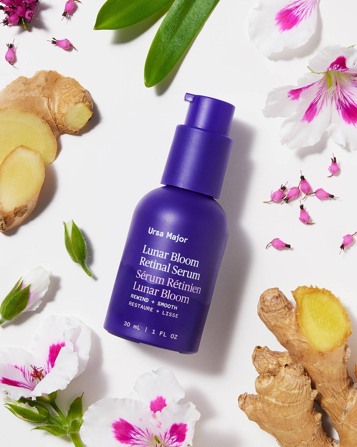 Ursa Major Lunar Bloom Retinol Serum bottle with ginger root and flowers on a white background