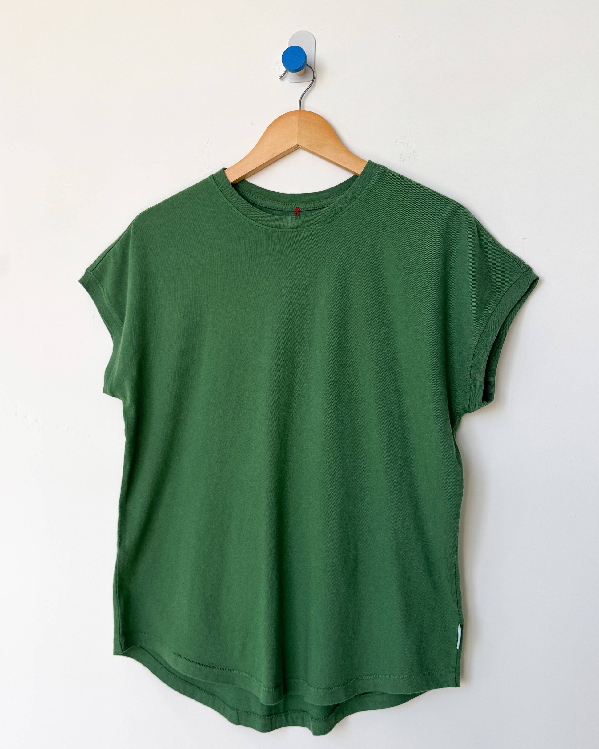 Green t-shirt on a wooden hanger against a white background