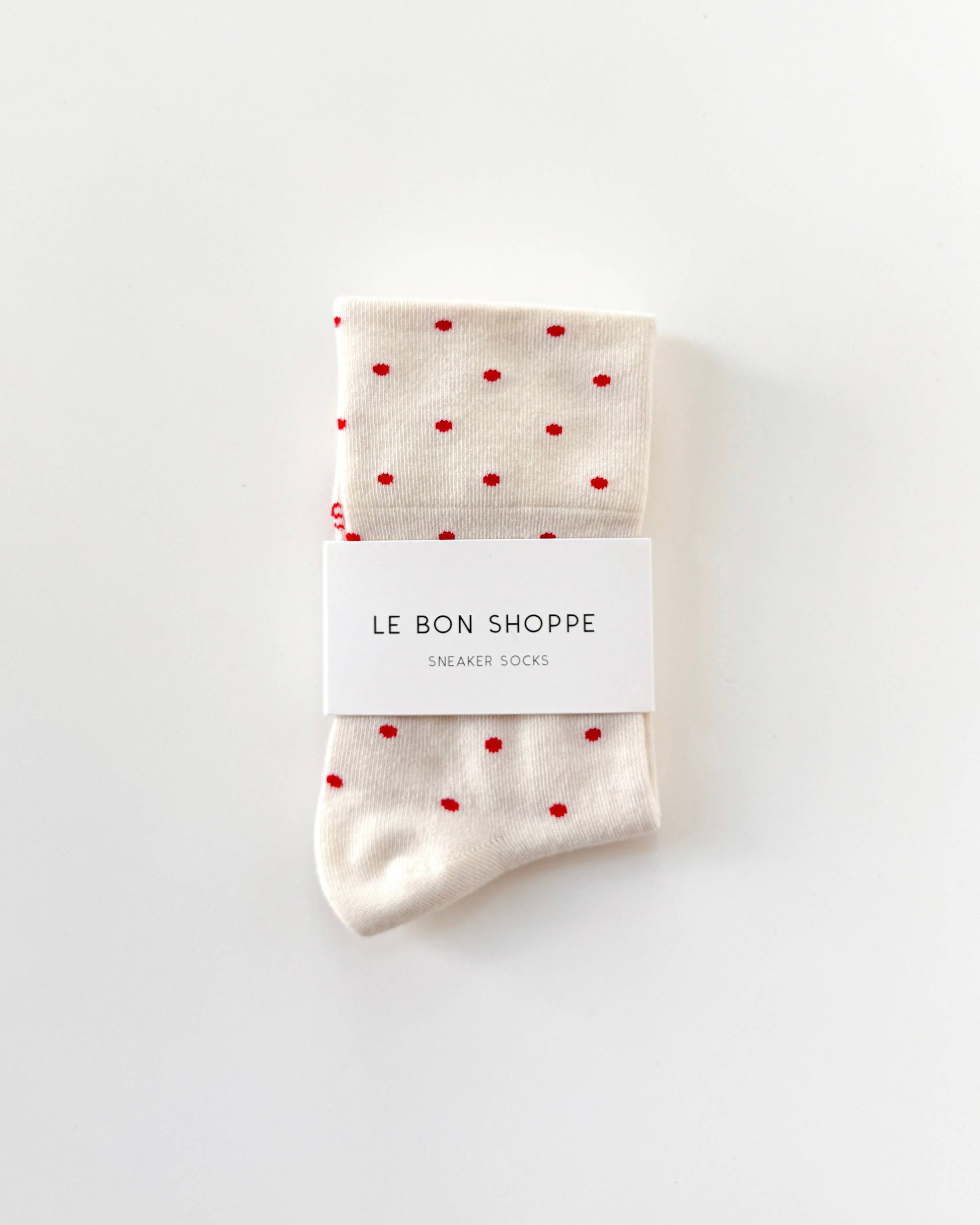 Pair of socks with red polka dots and a visible brand label on a white background