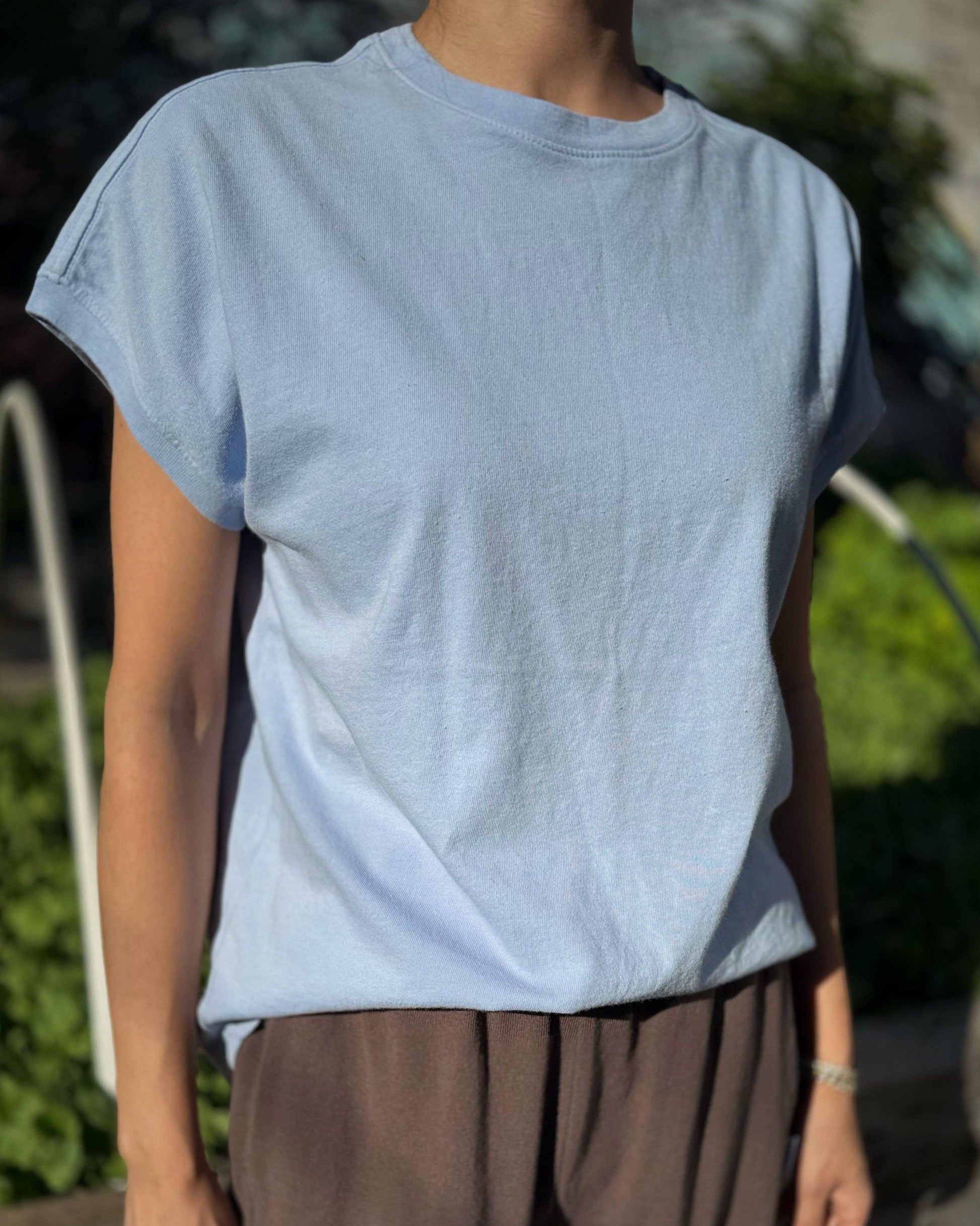 Person wearing a light blue t-shirt and brown pants outdoors