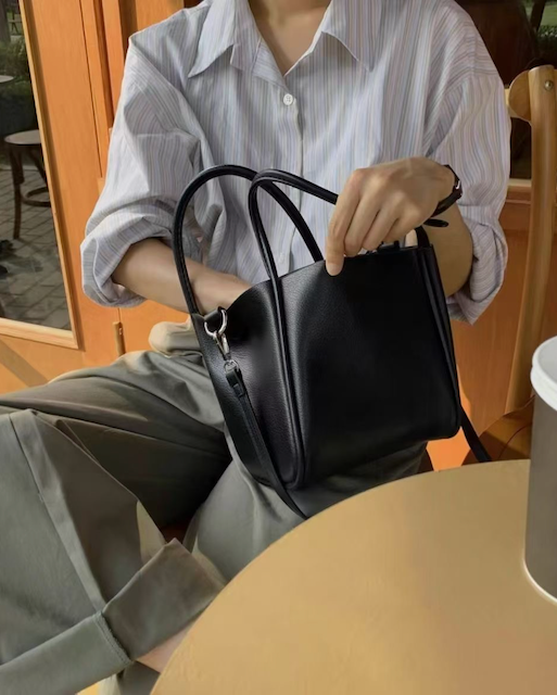 Person holding a black handbag in an indoor setting